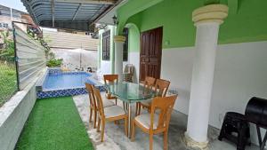a patio with a glass table and chairs and a pool at Homestay Segamat - Teratak Impian in Segamat