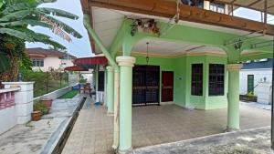 a green building with columns and a porch at Homestay Segamat - Teratak Impian in Segamat