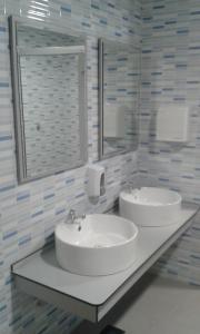 een badkamer met 2 wastafels en een spiegel bij Albergue Folgueira in Portomarin