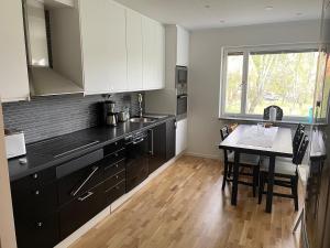 a kitchen with black cabinets and a table and a window at Newly renovated, spacious flat! in Uppsala