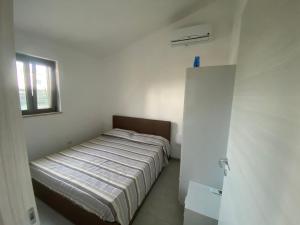 ein Bett in einem weißen Zimmer mit einem Fenster in der Unterkunft Villa VAdel Zambrone Marina in Zambrone