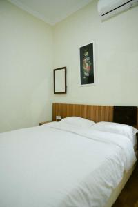 1 cama blanca en un dormitorio con una foto en la pared en Indise House at Hamsa Putih Yogyakarta, en Yogyakarta 24 fotos más