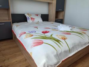a bed with a white blanket with flowers on it at Unique apartments in Timişoara
