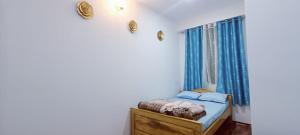 a bedroom with a bed and a window with blue curtains at Green heaven homestay in Kalimpong +10 photos