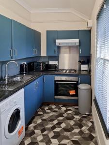 a kitchen with blue cabinets and a washing machine at Evo Stays - 2 bedroom, 2 mins walk to Station in Gravesend