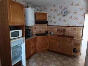 a small kitchen with wooden cabinets and a microwave at La Maison de Falaise in Falaise