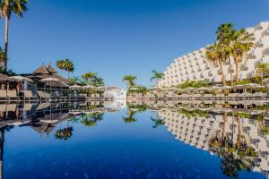widok na hotel z palmami i zbiornikiem wodnym w obiekcie Landmar Playa La Arena w mieście Puerto de Santiago