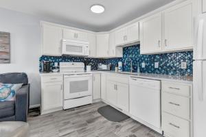 a kitchen with white cabinets and white appliances at Oceanview Condo - Sea Coast Suites 18 in Surf City, NC in Surf City
