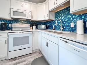 a white kitchen with white cabinets and a sink at Oceanview Condo - Sea Coast Suites 18 in Surf City, NC in Surf City +25 photos