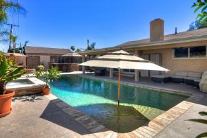a swimming pool with an umbrella and a house at F-20 Paradise Pier in Anaheim