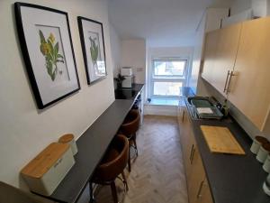 a kitchen with a black counter and stools in it at Seashell Apartment in Barmouth