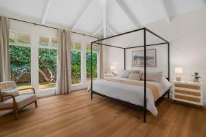 a bedroom with a canopy bed and a chair at F-71 Queens Bath Point in Princeville +23 photos