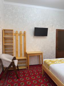 a room with a bed and a desk and a tv at SAID-MAXSUM in Khiva