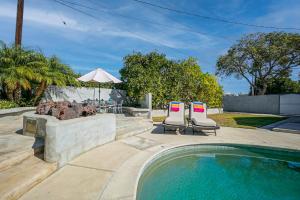 a swimming pool with two chairs and an umbrella at F-65 Adventure House in Anaheim