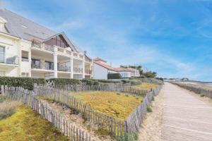 a house with a wooden fence next to a sidewalk at L'Athéna By Tranquil at Home in Pornichet
