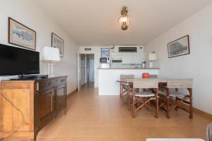 a living room with a television and a table with chairs at L'Athéna By Tranquil at Home in Pornichet