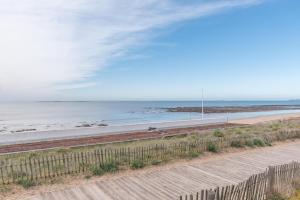a beach with a fence next to the ocean at L'Athéna By Tranquil at Home in Pornichet +5 photos
