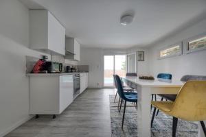a kitchen with white cabinets and a table and chairs at Maison ANA in Équemauville