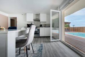 a kitchen and dining room with a view of a swimming pool at Maison ANA in Équemauville