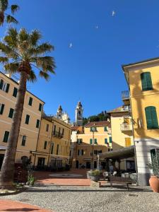 a group of buildings with a palm tree and a bench at Hotel Mambo in Laigueglia