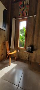Holzzimmer mit einem Stuhl und einem Fenster in der Unterkunft Casa Cor Tiradentes in Tiradentes