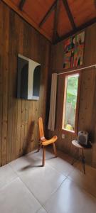 Holzzimmer mit einem Stuhl und einem Fenster in der Unterkunft Casa Cor Tiradentes in Tiradentes