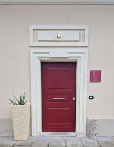 a red door on a white building with a potted plant at Camere AL Borgo in Santa Sofia