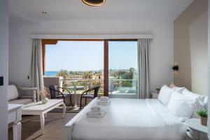 a bedroom with a large white bed and a living room at Georgia's Garden by Omilos Hotels in Amoudara Herakliou