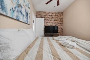 a bedroom with a bed and a tv on a brick wall at Spacious & Stylish 2BR Apartment Near Manhattan in Jersey City