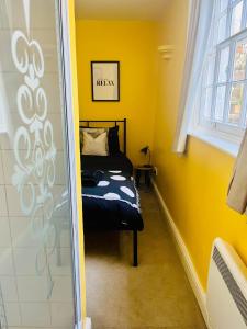 a yellow room with a bed and a window at The Beach Retreat - A Bijou Seaside Maisonette in Rustington