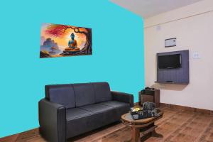 Una sala de estar con un sofá negro y un televisor. en A Golden Puri Eco Resort, en Puri