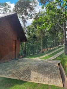 a brick house with a brick driveway next to a field at Chalé HOSPEDAGEM in Rio Bananal