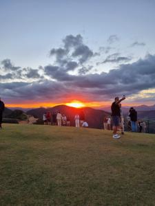 a group of people standing on a hill watching the sunset at Chalé HOSPEDAGEM in Rio Bananal +1 photo