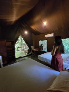 a woman standing in a room with two beds at Powerhouse River Resort in Eheliyagoda