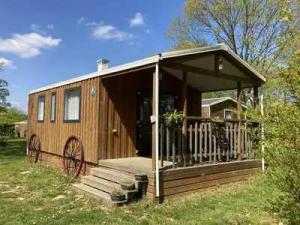 a wooden cabin with a porch on a field at Camping 3 étoiles - eed0ca in Priziac