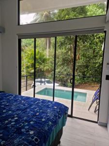 a bedroom with a bed and a view of a swimming pool at Plaza Tucanito - jungle up your life in Cahuita