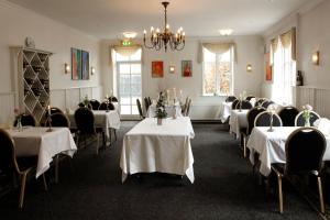Aars Hotel في Års: غرفة طعام بطاولات بيضاء وكراسي وثريا