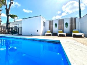a swimming pool with two chairs next to a building at GATU Villa Serena piscina privada mayores de 25 años y familias in Chiclana de la Frontera