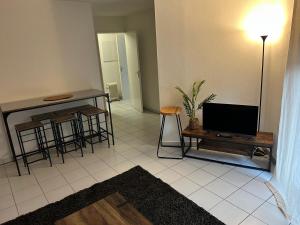 a living room with a tv and a table and stool at Appartement deux chambres jardin parking in Portet-sur-Garonne