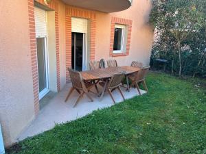 a wooden table and chairs on a patio at Appartement deux chambres jardin parking in Portet-sur-Garonne