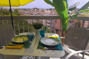 a table with plates and glasses on a balcony at Charming studio - 2 pers close to Cannes in Mandelieu-La Napoule