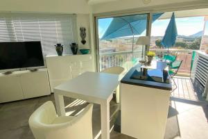a dining room with a white table and chairs and a balcony at Charming studio - 2 pers close to Cannes in Mandelieu-La Napoule