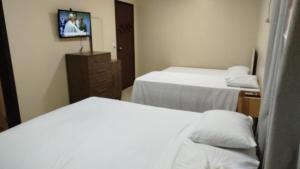a hotel room with two beds and a tv at Suites da Gladys in Foz do Iguaçu