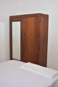 a bedroom with a wooden cabinet and a white bed at Peradeniya-Kandy Home Stay in Peradeniya +11 photos