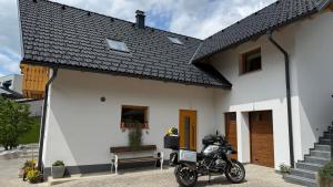 a motorcycle parked in front of a white house at Slosarjeva Holiday House - Alpine View & Modern Comfort in Preddvor