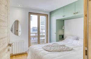 a bedroom with a large white bed with a mirror at Huxa Appt Megève Centre in Megève