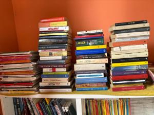 a stack of books sitting on a shelf at Casa accogliente sul naviglio in Milan