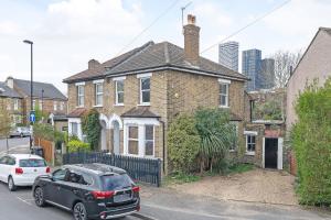 a black car parked in front of a brick house at Beautiful Large Bedrooms in South Norwood