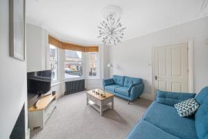 a living room with two blue couches and a table at Beautiful Large Bedrooms in South Norwood