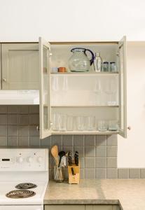 a kitchen with white cabinets with glasses and utensils at Island Vista - Waterfront Condo in Tofino +33 photos